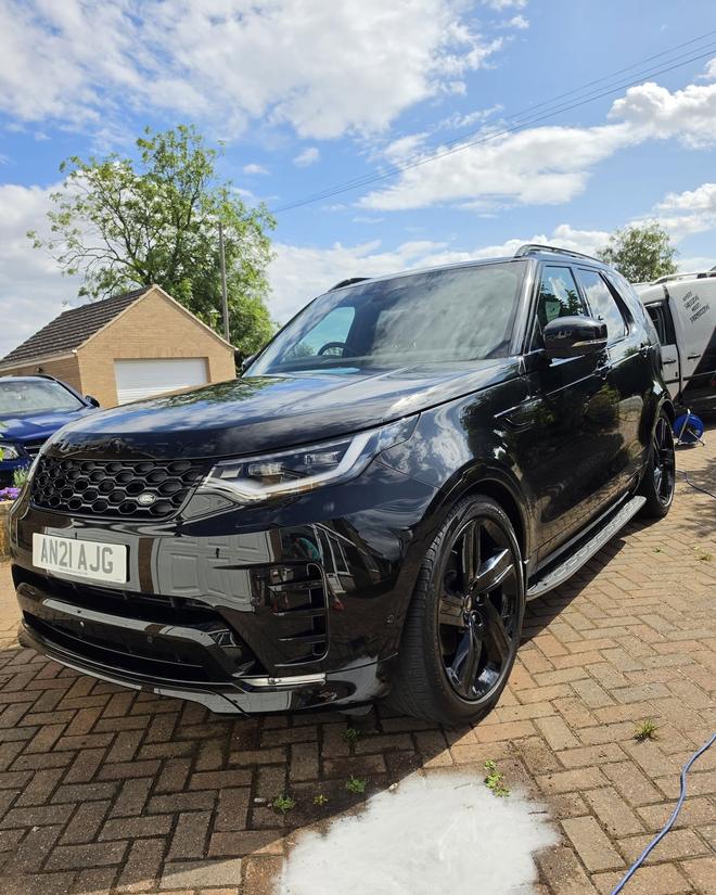 A black Land Rover Discovery after detailing, glossy paintwork reflecting the sky