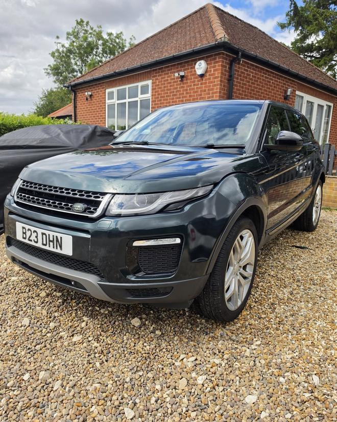 A dark green Range Rover Evoque after a full valet, parked on gravel