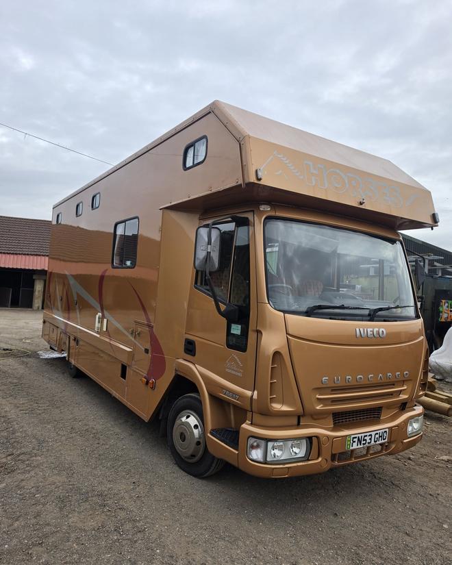 A gold horsebox lorry after an exterior valet, parked outside a stable yard