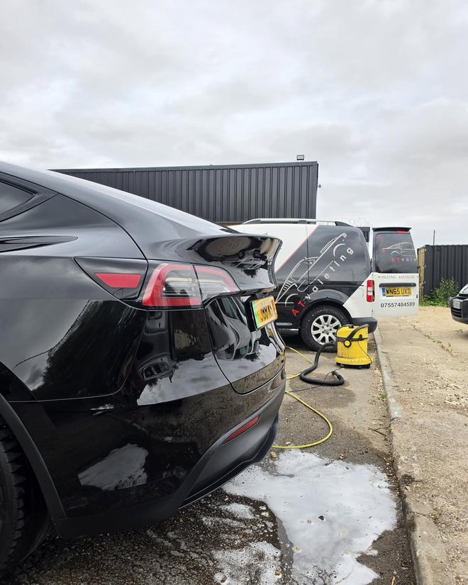 A black Tesla Model X being valeted next to the A T Valeting van and equipment