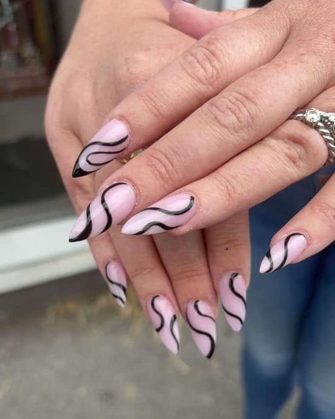 Pale pink nails with a bold black swirl line design