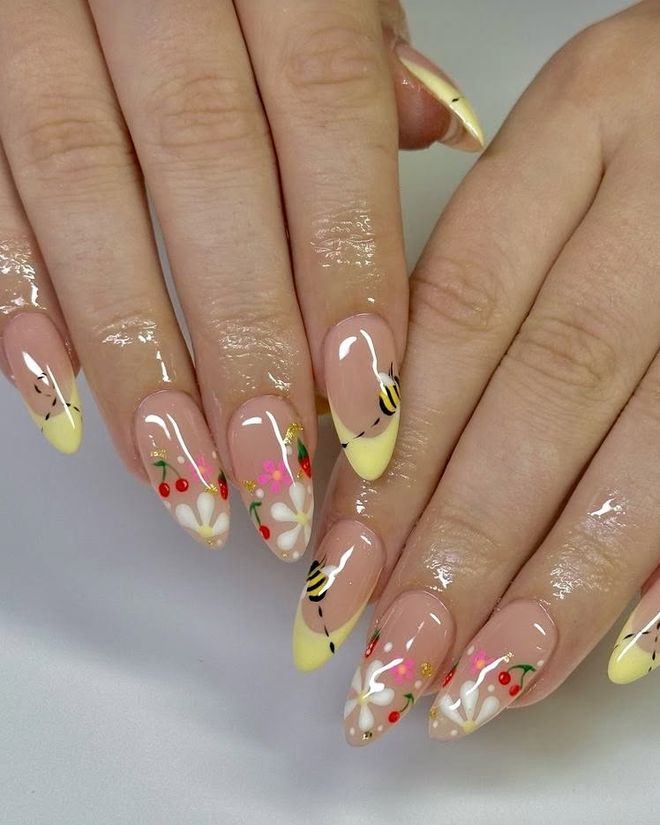 Pale yellow French tips with hand-painted daisies, cherries and a bumblebee